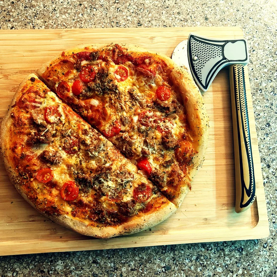 Pizza halves next to the hatchet on a cutting board